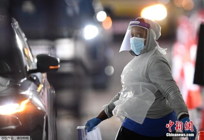 當(dāng)?shù)貢r(shí)間12月18日，英國(guó)政府公布的數(shù)據(jù)顯示，當(dāng)天英國(guó)新增奧密克戎毒株感染病例10059例。鑒于奧密克戎毒株感染病例激增，住院人數(shù)不斷上升，倫敦市長(zhǎng)宣布倫敦進(jìn)入“重大事故”狀態(tài)。圖為倫敦的一個(gè)免下車檢測(cè)中心，一名醫(yī)務(wù)工作者正準(zhǔn)備對(duì)司機(jī)進(jìn)行核酸檢測(cè)。