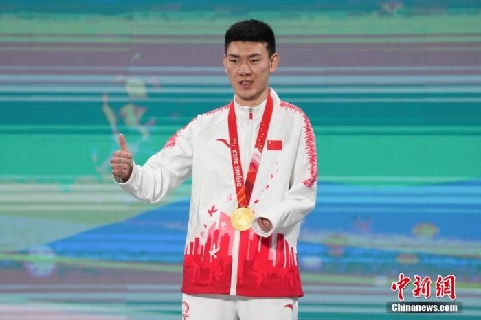 3月6日，梁景怡在延慶頒獎廣場領(lǐng)獎臺上豎起大拇指。當日，在國家高山滑雪中心舉行的北京2022年冬殘奧會殘奧高山滑雪男子超級大回轉(zhuǎn)—站姿決賽中，中國選手梁景怡奪得冠軍。 <a target='_blank' href='/'>中新社</a>記者 楊華峰 攝