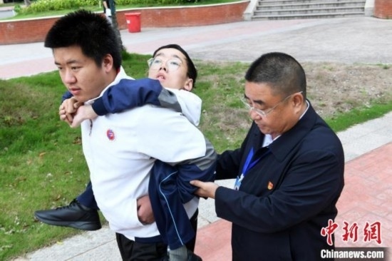 朱金祥背著鐘華強(qiáng)去教室上課的路上，也經(jīng)常碰到值班的校領(lǐng)導(dǎo)和老師前來(lái)搭把手。 卓忠偉 攝