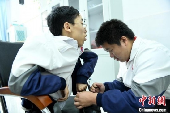 江西省南康中學(xué)北校區(qū)的高三學(xué)生朱金祥(右)正在給鐘華強(qiáng)(左)系好鞋帶。 卓忠偉 攝