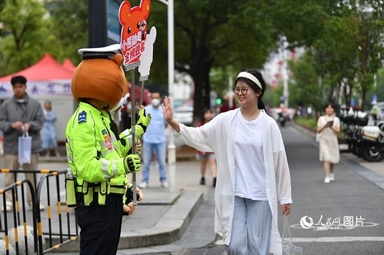 6月7日上午9時(shí)，隨著鈴聲的響起，2023年江西高考正式開(kāi)考，江西省的53.57萬(wàn)考生以縣（區(qū)）為單位隨機(jī)安排在全省256個(gè)考點(diǎn)、18968個(gè)考場(chǎng)參加高考。圖為“小熊交警”和考生擊掌鼓勵(lì)。 人民網(wǎng)記者 時(shí)雨攝