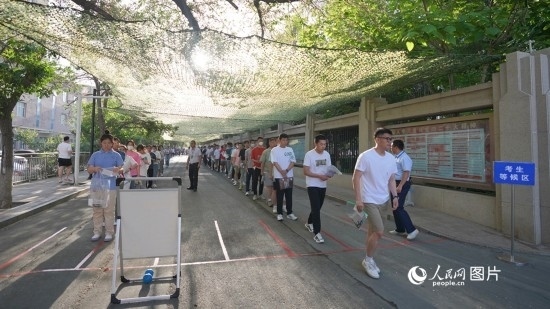 6月7日，烏魯木齊市第七十中學(xué)門(mén)口，考生們有序進(jìn)入考場(chǎng)。人民網(wǎng) 李欣洋攝