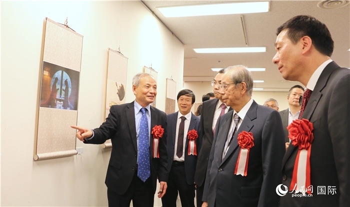 “湖州印象”攝影展主創(chuàng)、世界華人攝影協(xié)會(huì)副會(huì)長(zhǎng)馮學(xué)敏向吳江浩大使、福田康夫前首相等嘉賓介紹展出作品。（人民網(wǎng) 許可攝）