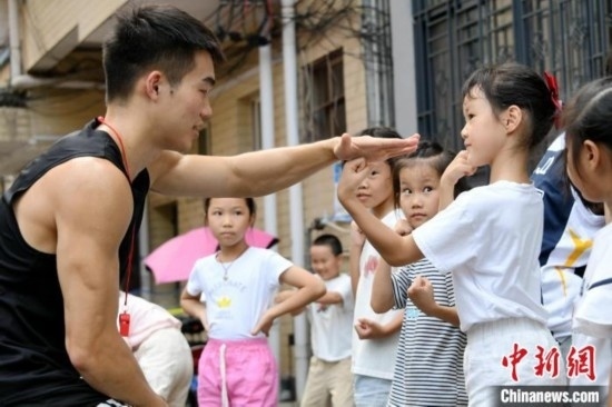 圖為大學生志愿者在組織孩子們參加體育健身活動。廖光福 攝