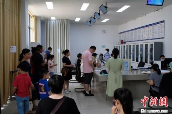 圖為在戶(hù)籍辦證廳內(nèi)排隊(duì)等待的家長(zhǎng)和孩子。劉俊聰 攝