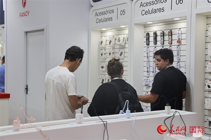 幾名參觀者在一個展臺前了解手機配件。（人民網(wǎng)記者 時元皓攝）