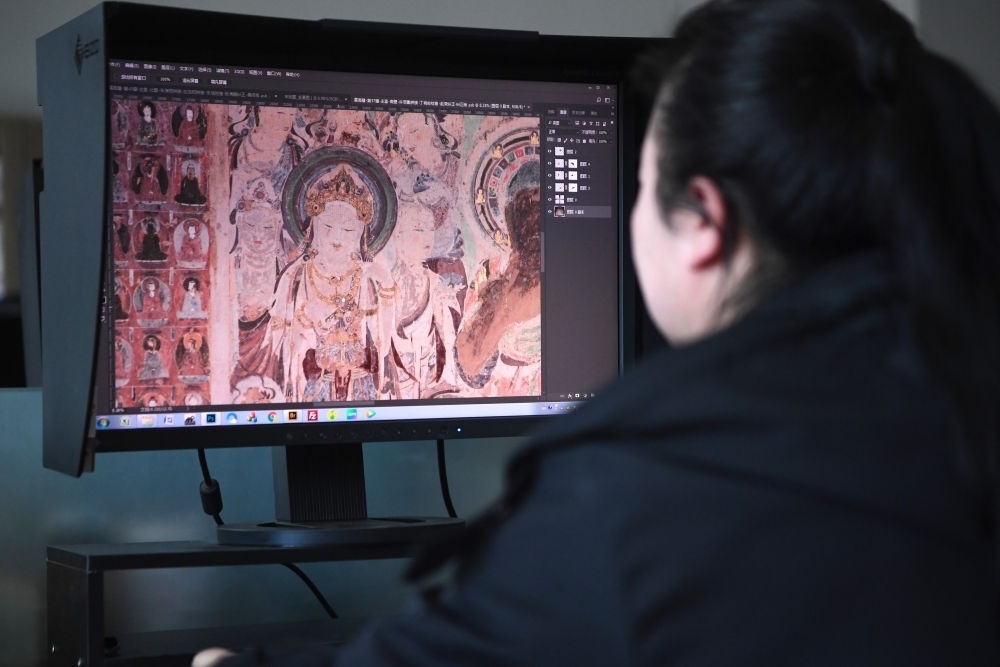 敦煌研究院文物數(shù)字化保護團隊圖像處理人員年海麗在拼接壁畫圖像（2023年4月25日攝）。數(shù)字化探索為莫高窟的保護與傳承開辟了全新路徑，數(shù)字技術讓敦煌文物走出洞窟，跨出國門，走向“永久保存、永續(xù)利用”。新華社記者 陳斌 攝