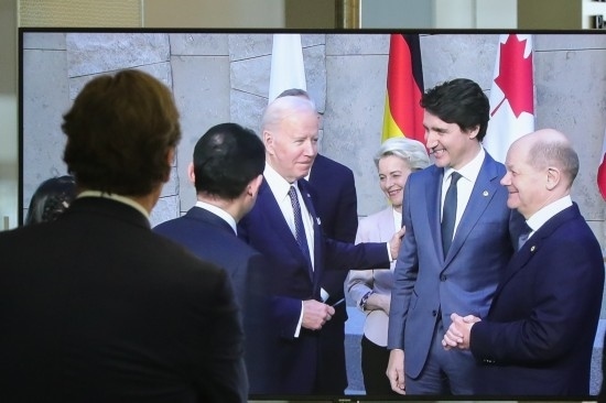 2022年3月24日，在比利時(shí)布魯塞爾的北約總部，一名男子觀看屏幕上美國總統(tǒng)拜登（右四）、歐盟委員會(huì)主席馮德萊恩（右三）、加拿大總理特魯多（右二）、德國總理朔爾茨（右一）出席七國集團(tuán)峰會(huì)合影儀式的畫面。新華社記者鄭煥松攝