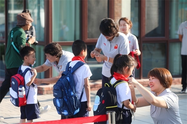 8月30日，雄安史家胡同小學(xué)學(xué)生體驗學(xué)校生活。老師為學(xué)生佩戴?；?。