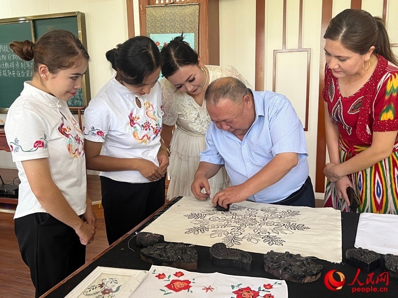 國家級非物質文化遺產模戳印花布技藝傳承人吾吉阿西木?吾舒爾展示模戳印花布的制作過程。人民網記者 常雪梅攝