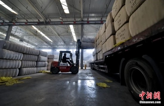新疆喀什綜合保稅區(qū)，喀什啟路國際貿(mào)易有限公司的倉庫內(nèi)，工人正在裝載從塔吉克斯坦和烏茲別克斯坦進(jìn)口的棉花。劉新攝