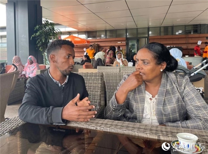 約漢斯（圖左）與德貝拉在友誼廣場咖啡廳交談。人民網(wǎng)記者 趙艷紅攝