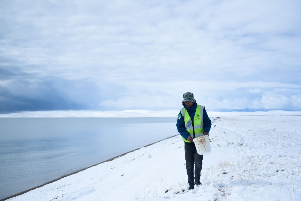 2021年10月20日，在青海省果洛藏族自治州瑪多縣扎陵湖鄉(xiāng)勒那村，三江源國家公園黃河源園區(qū)生態(tài)管護員在扎陵湖邊撿拾垃圾。新華社記者 張龍 攝
