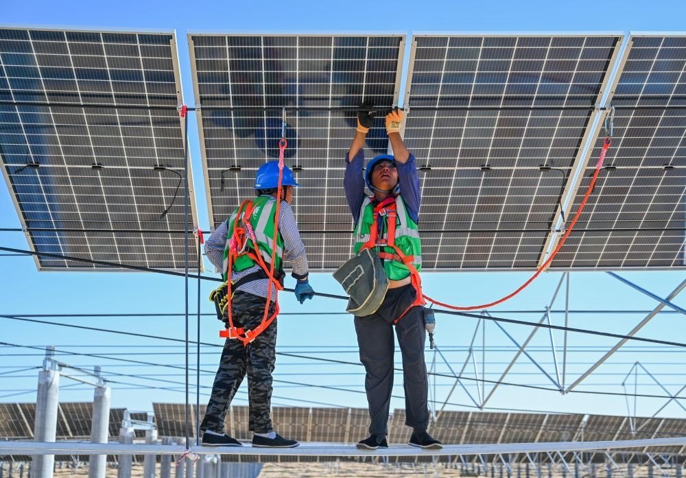 2023年7月22日，工人在位于內(nèi)蒙古杭錦旗庫布其沙漠億利生態(tài)示范區(qū)的蒙西基地庫布其200萬千瓦光伏治沙項目工地安裝光伏板。新華社記者 劉磊 攝