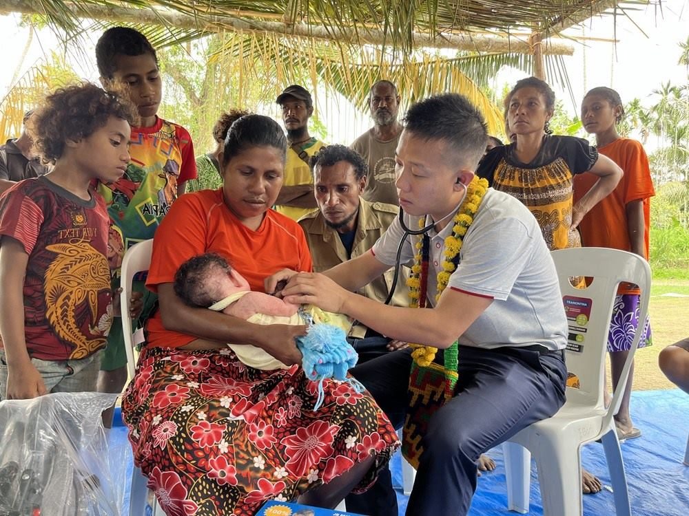 2023年8月5日，在巴布亞新幾內(nèi)亞中央省的一個(gè)村莊里，第12批援巴新中國(guó)醫(yī)療隊(duì)副隊(duì)長(zhǎng)、新生兒科副主任醫(yī)師劉振球?yàn)楫?dāng)?shù)貗雰郝犜\檢查。新華社發(fā)（第12批援巴新中國(guó)醫(yī)療隊(duì)供圖）