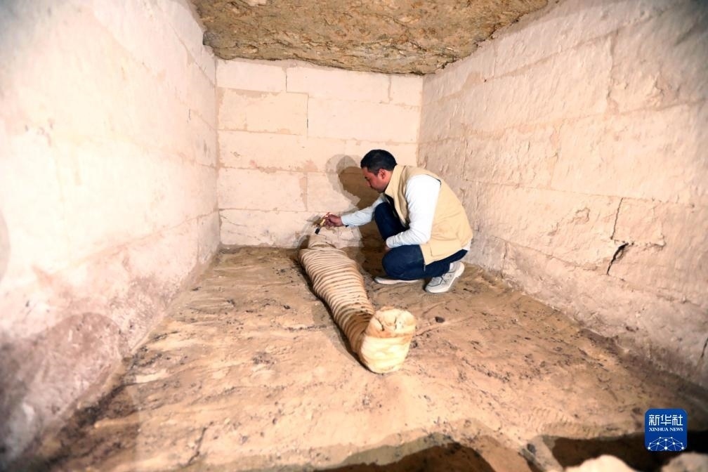 10月15日，在埃及明亞省考古現(xiàn)場，考古人員清理一座石鑿墓中的木乃伊。新華社發(fā)（艾哈邁德·戈馬攝）