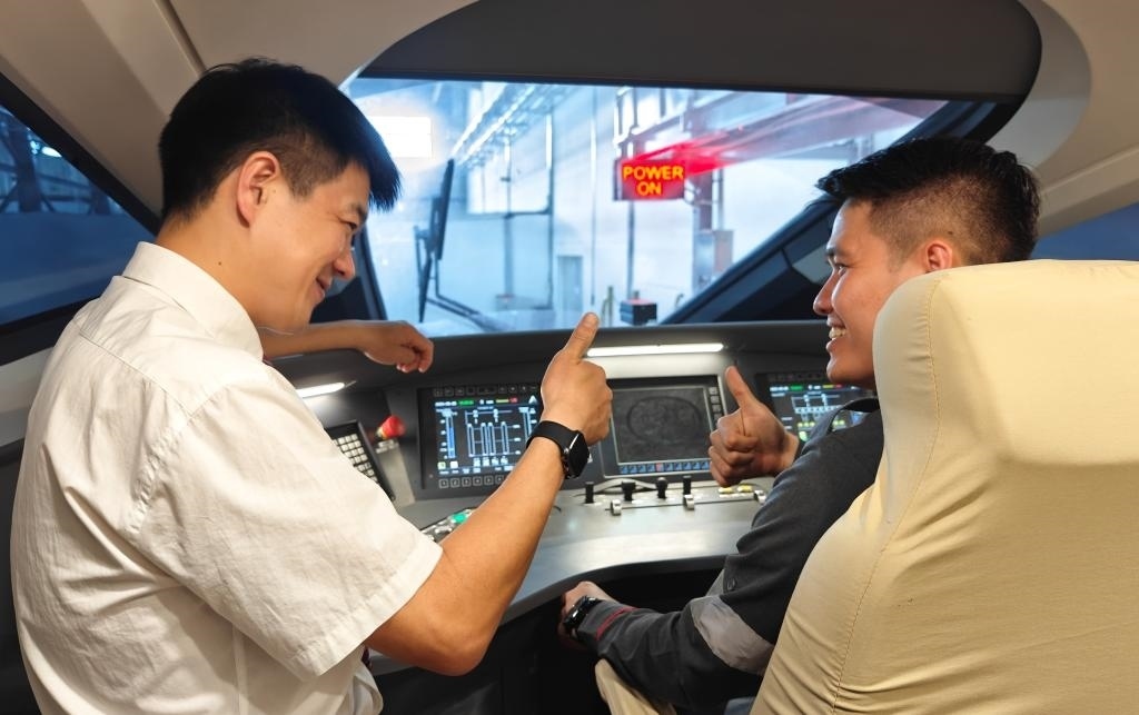 8月25日，在印度尼西亞萬隆的雅萬高鐵德卡魯爾動(dòng)車所內(nèi)，中國師傅穆振（左）在向印尼火車司機(jī)塞蒂亞萬講解動(dòng)車組出庫前的上電作業(yè)。