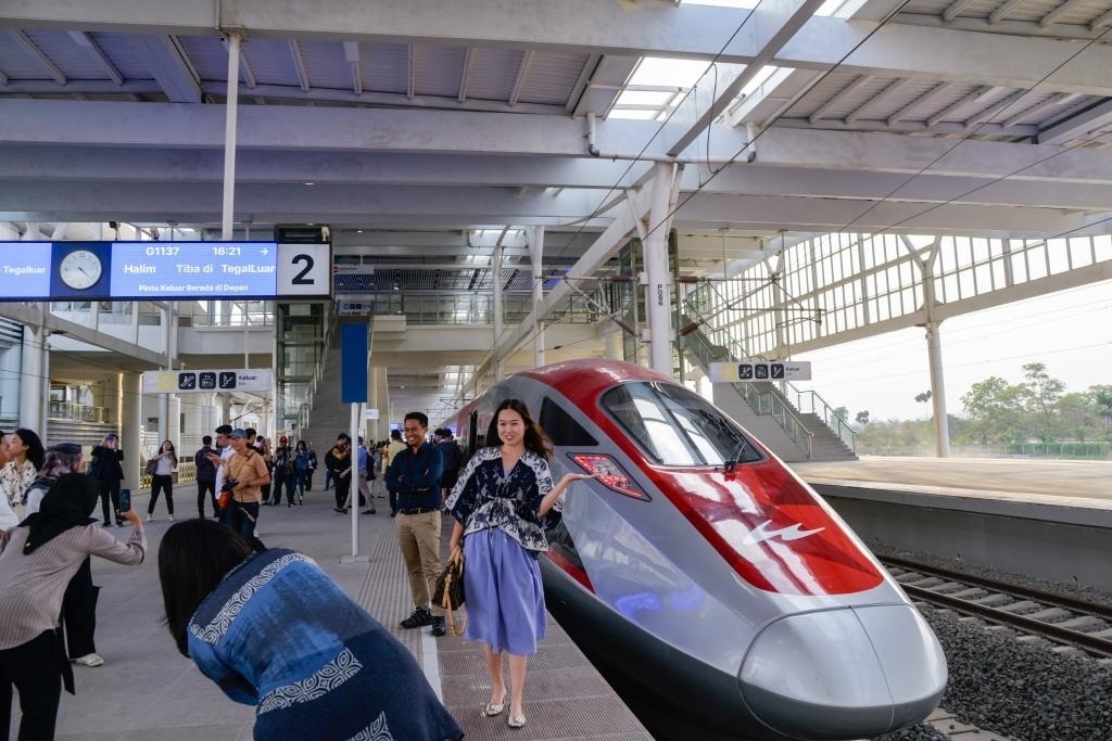 10月17日，在印度尼西亞萬隆德卡魯爾站，乘客在站臺上和雅萬高鐵高速動(dòng)車組列車合影。
