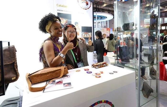 11月6日，一位參觀者（右）在第六屆進博會國家展南非展臺試戴傳統(tǒng)首飾。