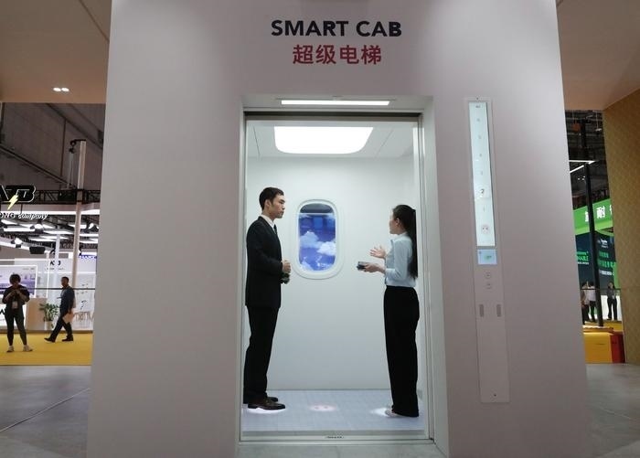 11月5日，工作人員（右）在第六屆進博會上向參觀者介紹奧的斯公司全新推出的超級電梯。