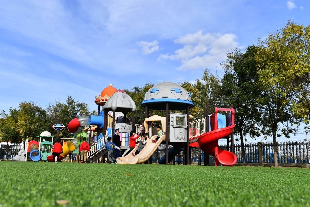 在山東省東營市墾利區(qū)楊廟社區(qū)幼兒園，孩子們在老師的帶領(lǐng)下進行戶外活動（2021年10月19日攝）。新華社記者 郭緒雷 攝