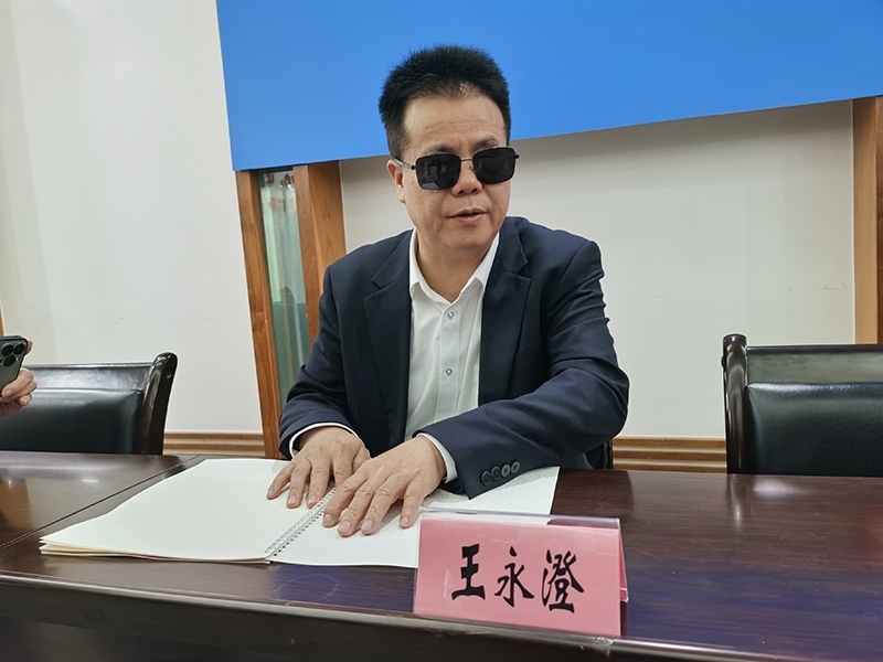 全國人大代表王永澄正在閱讀盲文版代表建議答復(fù)。本報記者 張 璁?dāng)z