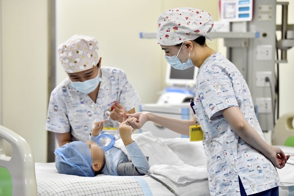 在山東省棗莊市婦幼保健院兒童ICU病房，醫(yī)護人員為完成靶向治療藥物諾西那生鈉的4歲脊髓性肌萎縮癥患兒加油鼓勁（2022年1月1日攝）。諾西那生鈉注射液是我國首個獲批治療脊髓性肌萎縮癥的進口藥物，2019年進入中國市場時，每針價格近70萬元。在2021年國家醫(yī)保目錄藥品談判中，以3.3萬元每針的價格進入新版醫(yī)保藥品目錄。新華社記者 郭緒雷 攝