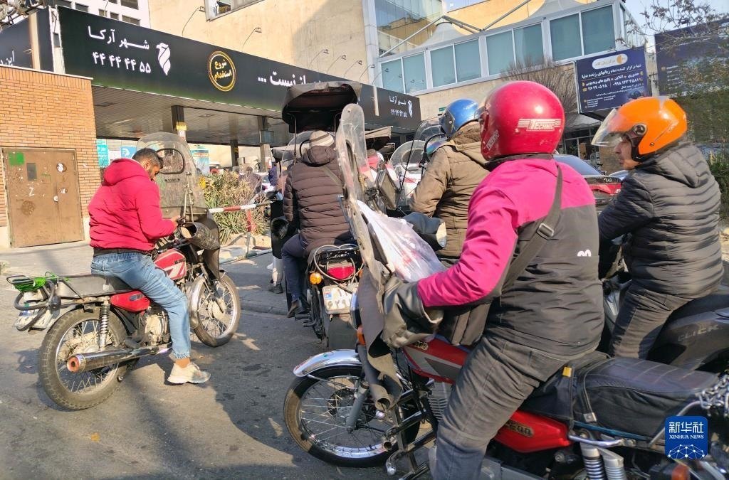 12月18日，摩托車在伊朗首都德黑蘭的一家加油站外等待加油。新華社記者 沙達提 攝