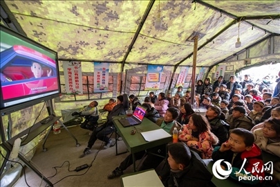 12月22日，在積石山縣大河家鎮(zhèn)大河村安置點(diǎn)，陸軍76集團(tuán)軍某旅搭建的“臨時(shí)學(xué)?！眱?nèi)，小朋友正在看動(dòng)畫(huà)片。人民網(wǎng)記者 翁奇羽攝