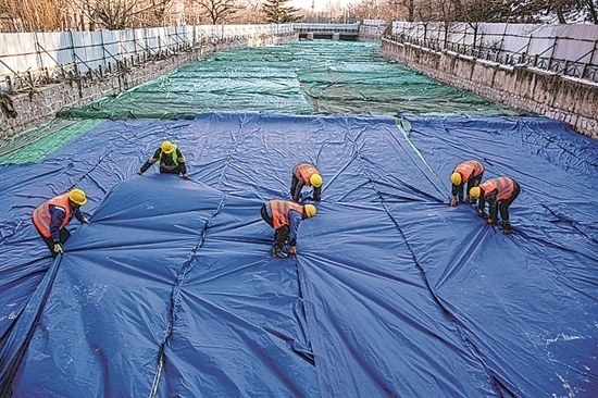 1月3日，房山區(qū)東風(fēng)街道，工人正在修復(fù)的河道內(nèi)給混凝土鋪設(shè)保溫布。