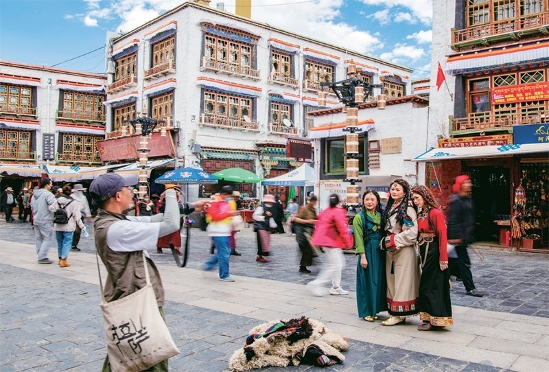 千年八廓街，見證民族團(tuán)結(jié)。2021年7月，習(xí)近平總書記來(lái)到位于西藏拉薩老城區(qū)的八廓街，感慨地說(shuō)：“千年八廓街，是我們各民族建起來(lái)的八廓街。各民族文化在這里交流交往交融，我們中華民族的大家庭在這里其樂融融?！眻D為2023年6月13日，游客身著藏裝在八廓街拍照留念。 新華社記者 姜帆/攝