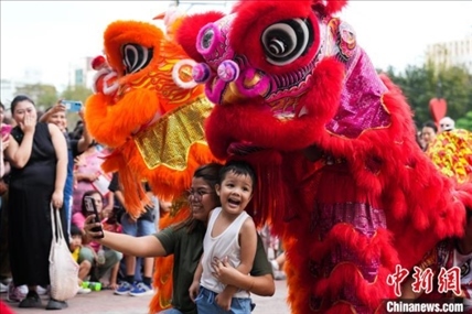 圖為舞獅表演吸引民眾合影。張興龍攝