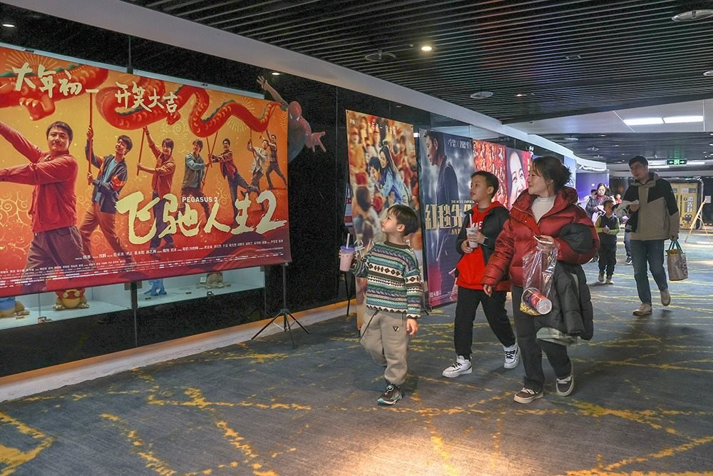 △ 2024年2月16日，在江西贛州一家電影院，觀眾從春節(jié)檔電影的宣傳展板前走過(guò)。