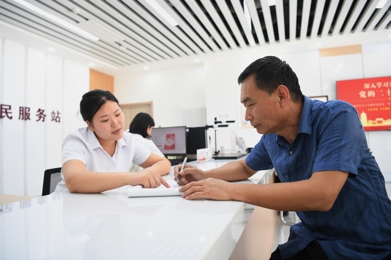 2023年5月23日，河北雄安新區(qū)容東片區(qū)南文營社區(qū)居民（右）在社區(qū)便民服務(wù)站辦理業(yè)務(wù)。