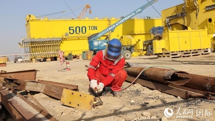 工人正在龍門吊吊裝現(xiàn)場切割金屬件。人民網(wǎng)記者管克江攝