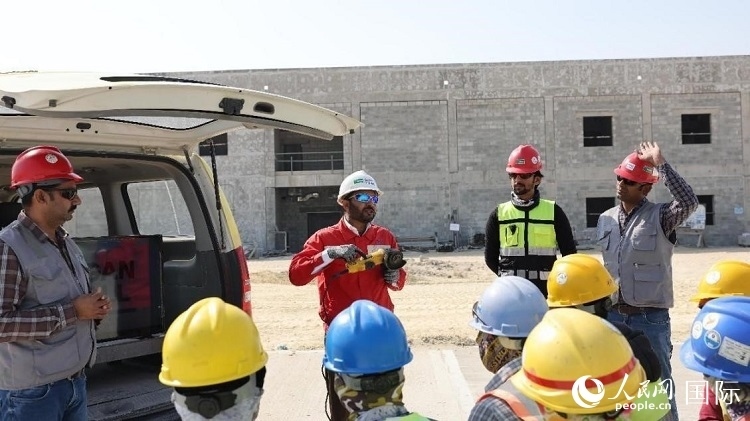 穆薩瓦爾(圖中紅衣人）現(xiàn)場演示工具操作規(guī)范。人民網(wǎng)記者 管克江攝