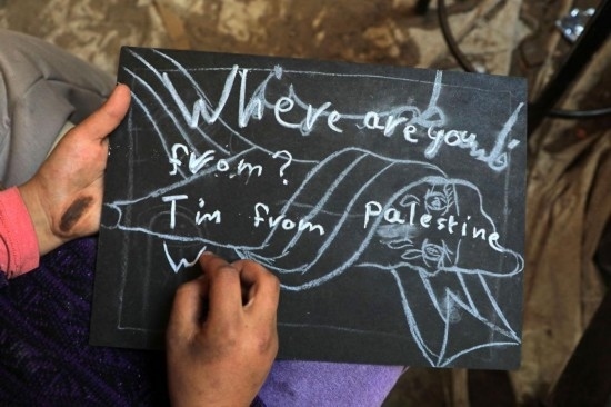 2023年12月28日，一名學(xué)生在加沙地帶南部城市拉法一所學(xué)校的臨時(shí)教室中寫(xiě)下“我來(lái)自巴勒斯坦”的字樣。新華社發(fā)（里澤克·阿卜杜勒賈瓦德攝）