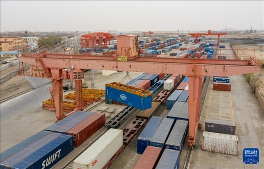 4月21日，二連浩特鐵路口岸龍門吊吊裝中歐班列集裝箱（無人機照片）。 新華社發(fā)（張海峰攝）