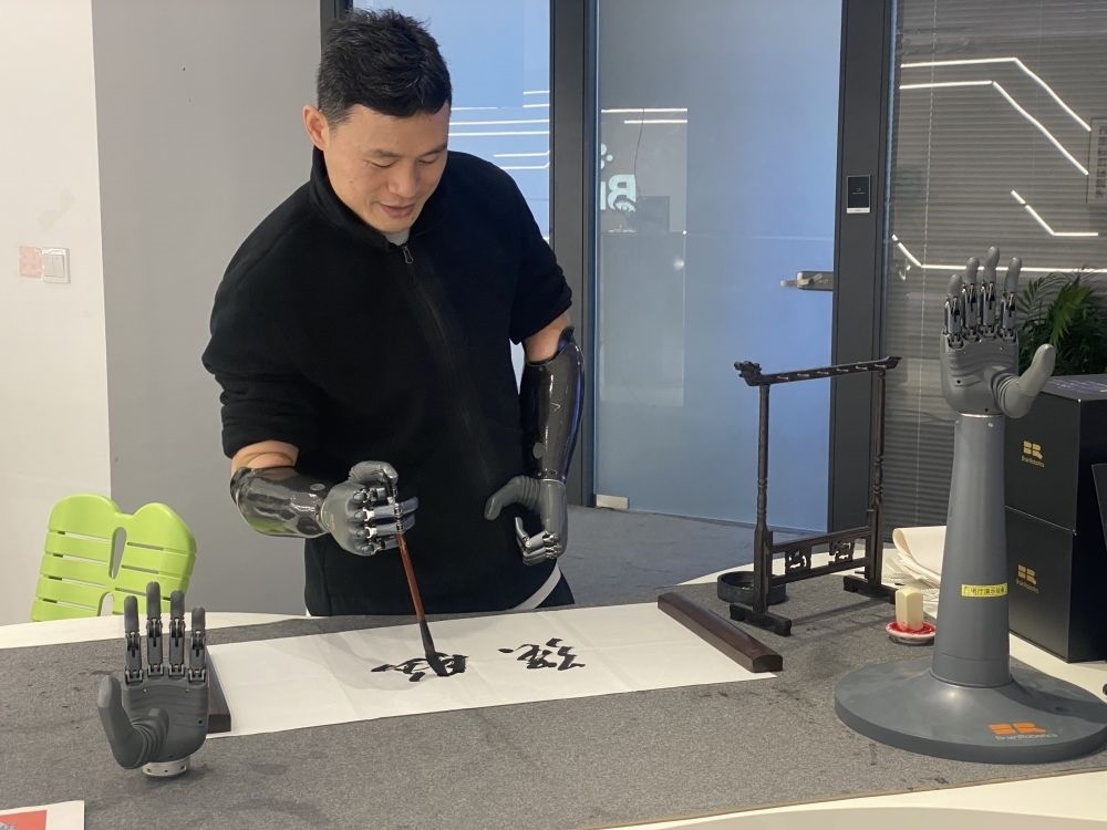 2024年3月29日，在浙江強腦科技有限公司展廳內(nèi)，失去雙手的產(chǎn)品體驗官倪敏成依靠智能仿生手寫毛筆字。新華社記者 魏一駿 攝