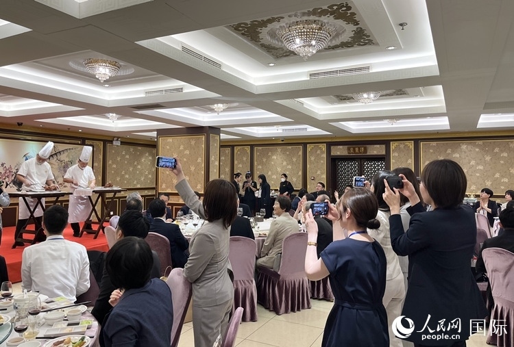 國家級非物質(zhì)文化遺產(chǎn)、全聚德片鴨工藝吸引代表團(tuán)成員拍照留念。