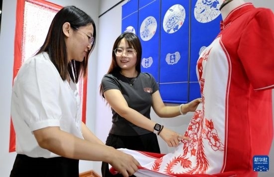 5月31日，在衡水市阜城縣一家剪紙工作室，游客在觀賞帶有剪紙?jiān)氐钠炫邸? width=