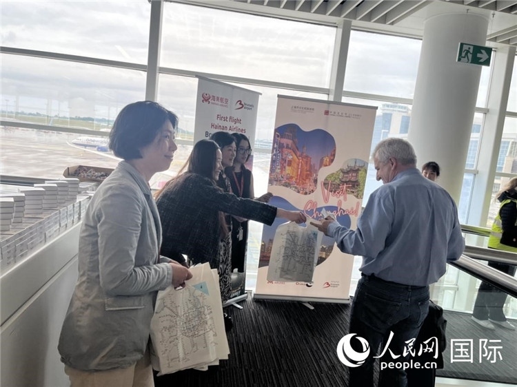 圖為工作人員向乘客發(fā)放復航首班禮物。 牛瑞飛攝