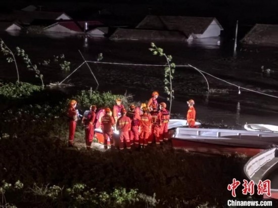  7月6日凌晨3時(shí)，在湖南岳陽(yáng)華容縣團(tuán)洲垸洞庭湖一線堤防，救援人員剛剛完成一次救援任務(wù)，遠(yuǎn)處是被淹的民房。中新社記者 白祖偕 攝