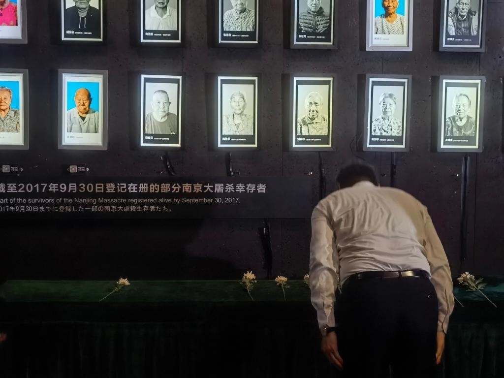 7月18日，人們向離世的南京大屠殺幸存者獻(xiàn)花、鞠躬。新華社記者邱冰清 攝