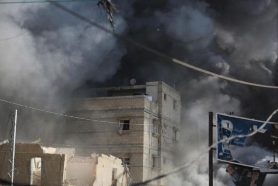 7月21日，在加沙地帶中部的努賽賴(lài)特難民營(yíng)，遭以軍空襲的建筑冒出滾滾濃煙。新華社發(fā)（馬爾萬(wàn)·達(dá)烏德攝）