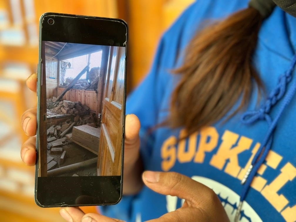 圖為7月17日拉毛東智在手機(jī)上找出地震后房屋受損的照片。新華社記者 張子琪 攝