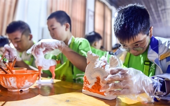 小朋友們在洛陽市孟津區(qū)朝陽鎮(zhèn)南石山村體驗(yàn)唐三彩素胎施釉技藝。圖片來源：視覺中國