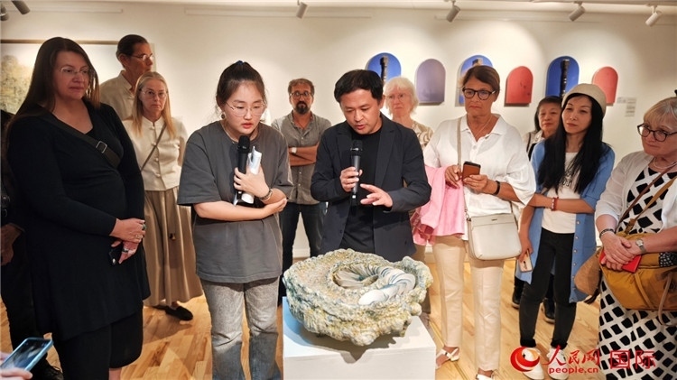 參展人、景德鎮(zhèn)陶瓷大學設(shè)計藝術(shù)學院副院長余劍峰（中）向來賓介紹參展作品。人民網(wǎng)記者 殷淼攝