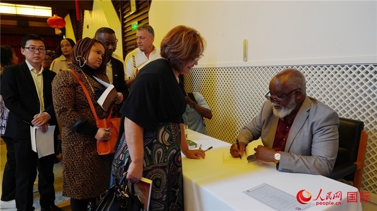 譚哲理在活動(dòng)現(xiàn)場(chǎng)簽名贈(zèng)書。人民網(wǎng) 劉暢攝