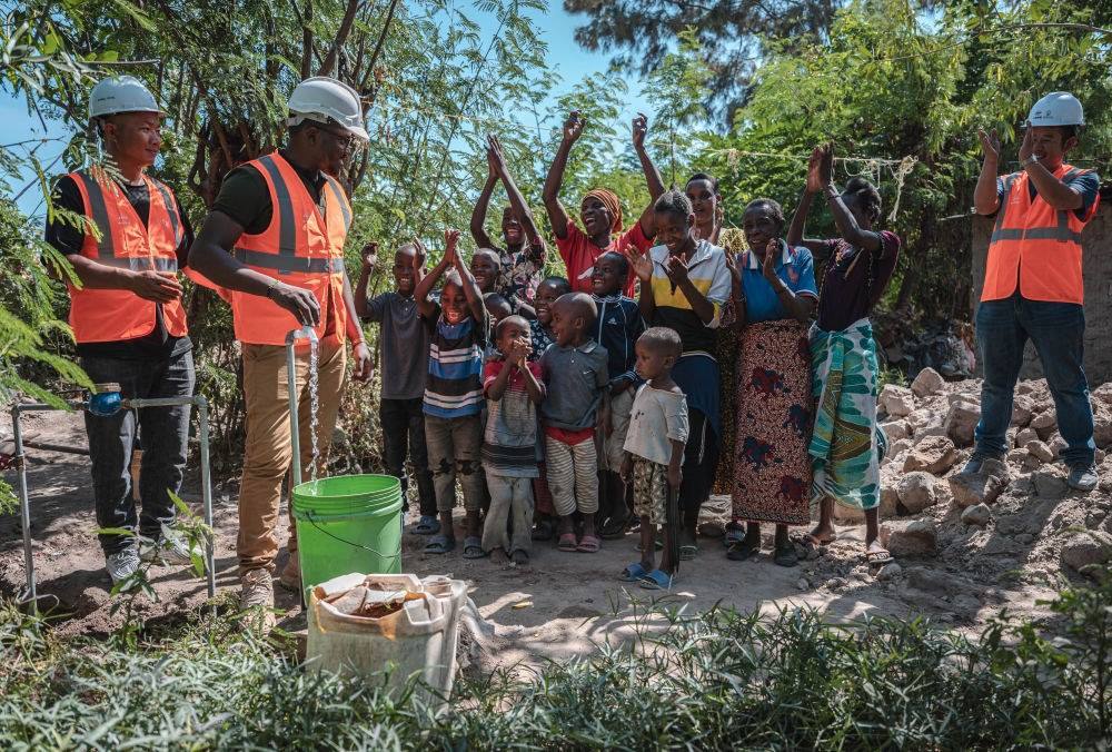 2023年6月13日，在坦桑尼亞姆萬扎省米松圭，工作人員接通水管后贏得當(dāng)?shù)鼐用窆恼茪g呼。新華社記者 王冠森 攝